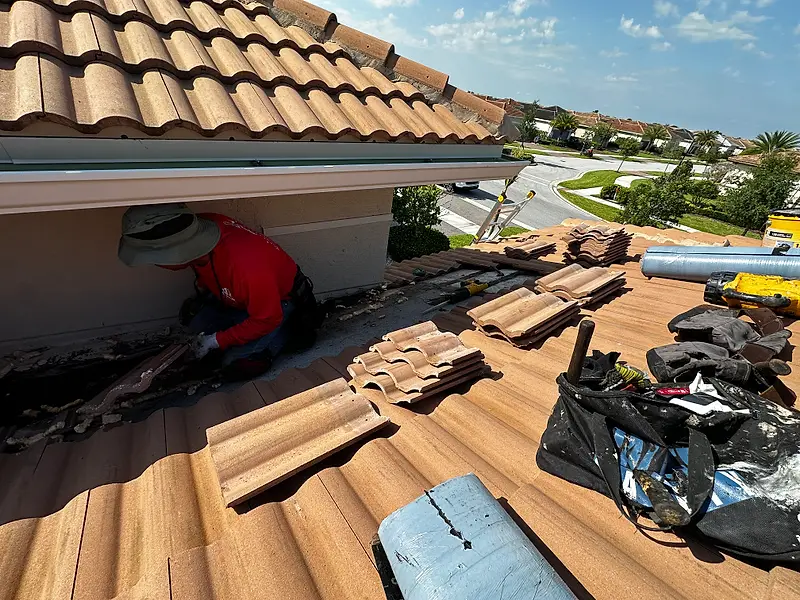 Remco roofer in a red shirt pulling old tile off a roof