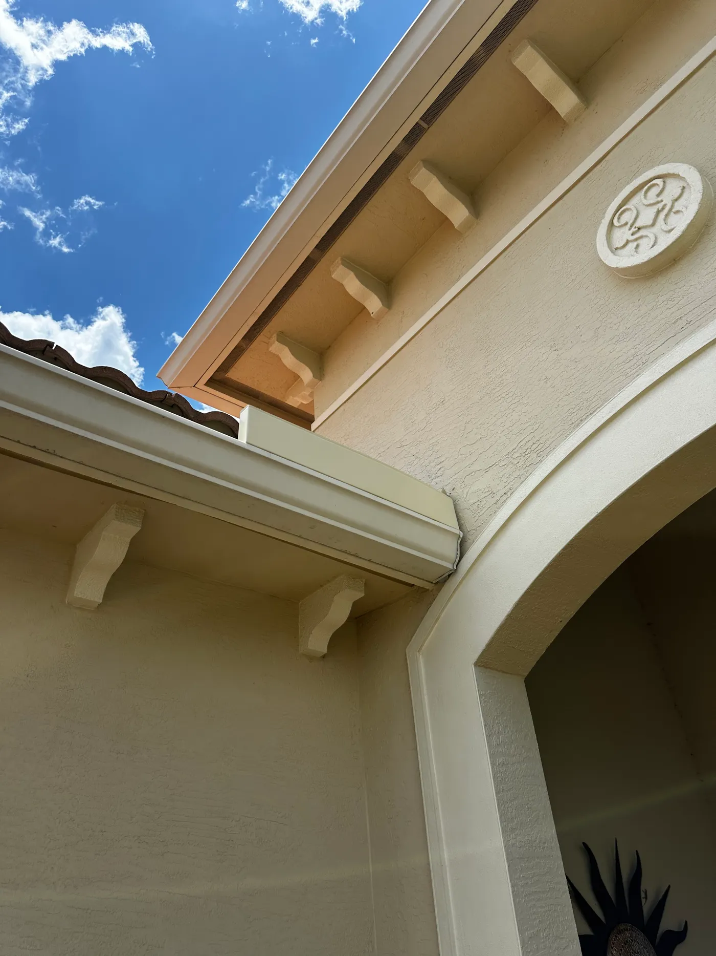 White seamless gutter under a tile roof edge on a stucco home