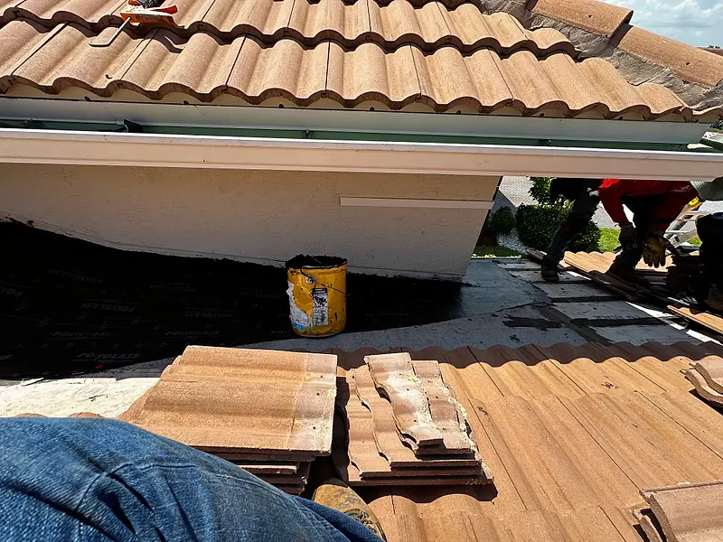 New tile stacked at a roof edge above a white gutter